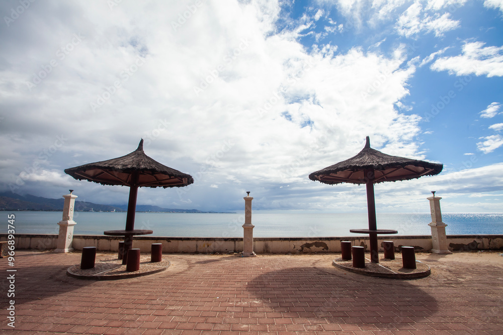 Gazebo with with traditional roof on the edge of Cristho Rei Beach in Dili, East Timor. Cristo Rei Beach is a beautiful beach tourist attraction in Dili and also home to the Christ the King Statue. Gazebo with with traditional roof on the edge of Cristho Rei Beach in Dili, East Timor. Cristo Rei Beach is a beautiful beach tourist attraction in Dili and also home to the Christ the King Statue.