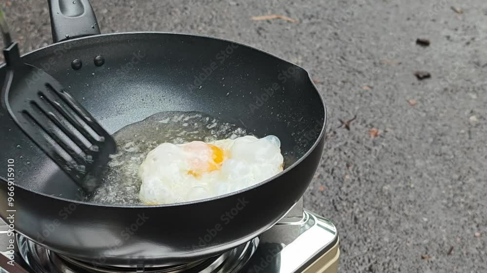 Fresh egg is fried in a frying pan outdoors with a sizzling. Fresh egg is fried in a frying pan outdoors with a sizzling.