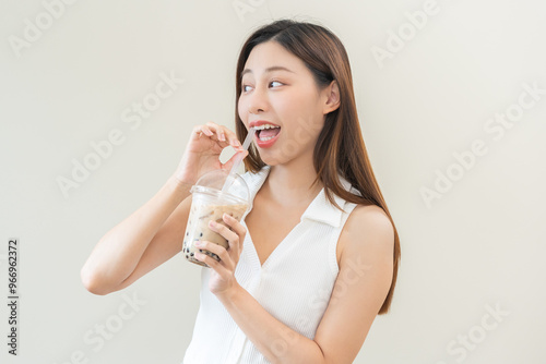 Beverage and food concept, Happy asian young woman hand holding plastic cup, glass of drink bubble, pearl milk tea with straw, cute girl drinking ice cold tea with tapioca boba ball popular in Taiwan.