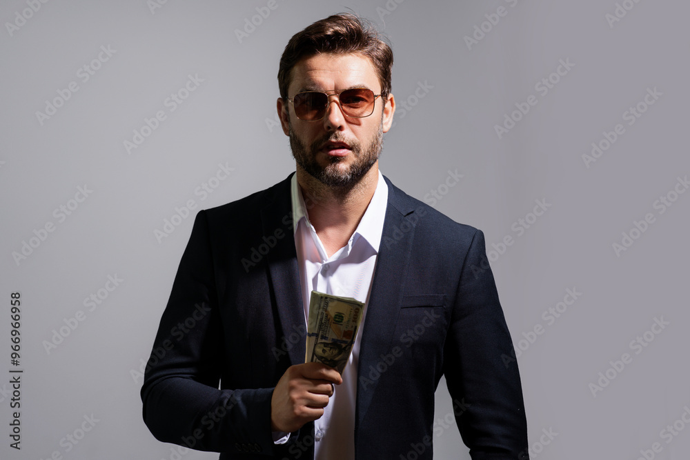 Man holding cash money in dollar banknotes on gray. Studio portrait of businessman with bunch of dollar banknotes. Dollar money concept. Career wealth business. Cash dollar banner. Man holding cash money in dollar banknotes on gray. Studio portrait of businessman with bunch of dollar banknotes. Dollar money concept. Career wealth business. Cash dollar banner.
