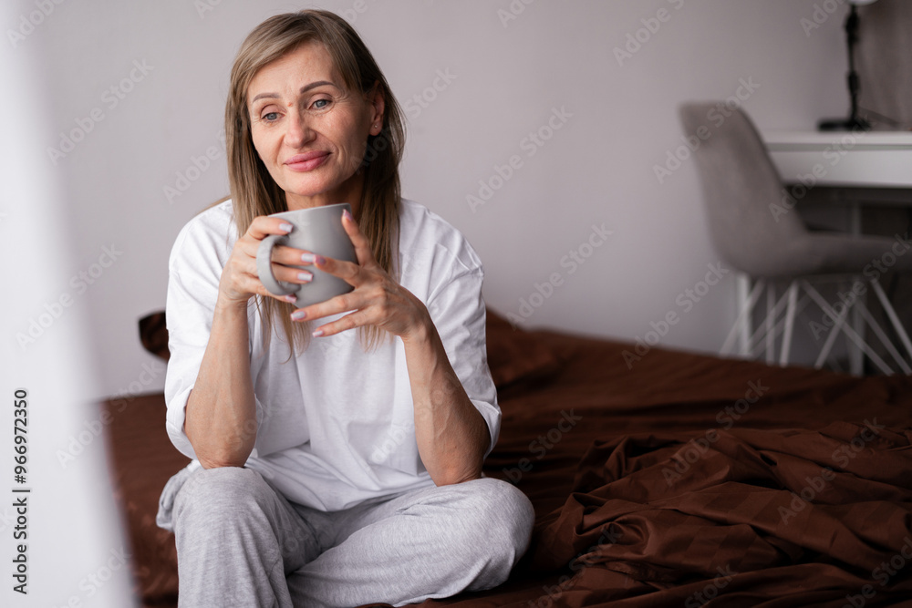 Senior attractive happy woman inhales the aroma of coffee in morning sitting in bed Senior attractive happy woman inhales the aroma of coffee in morning sitting in bed