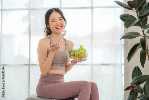 Fitness loving young asian woman sitting eating salad, health concept, exercise, healthy eating