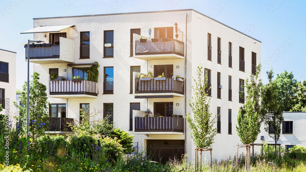 Fototapeta premium Modern Residential Building Apartment Exterior with Green Landscaping in Germany Munich. Modern Facade of Low rise Multi Storey Building with Flat Roof, Balcony Terrace and Urban Garden.