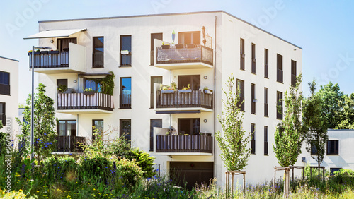 Modern Residential Building Apartment Exterior with Green Landscaping in Germany Munich. Modern Facade of Low rise Multi Storey Building with Flat Roof, Balcony Terrace and Urban Garden.