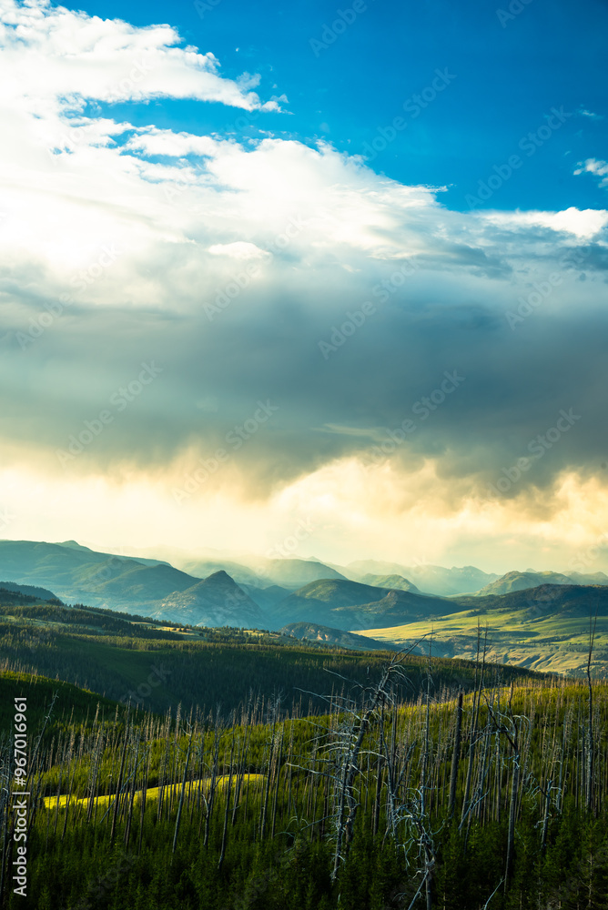 Cloud-covered mountains in Yellowstone under a bright sky.