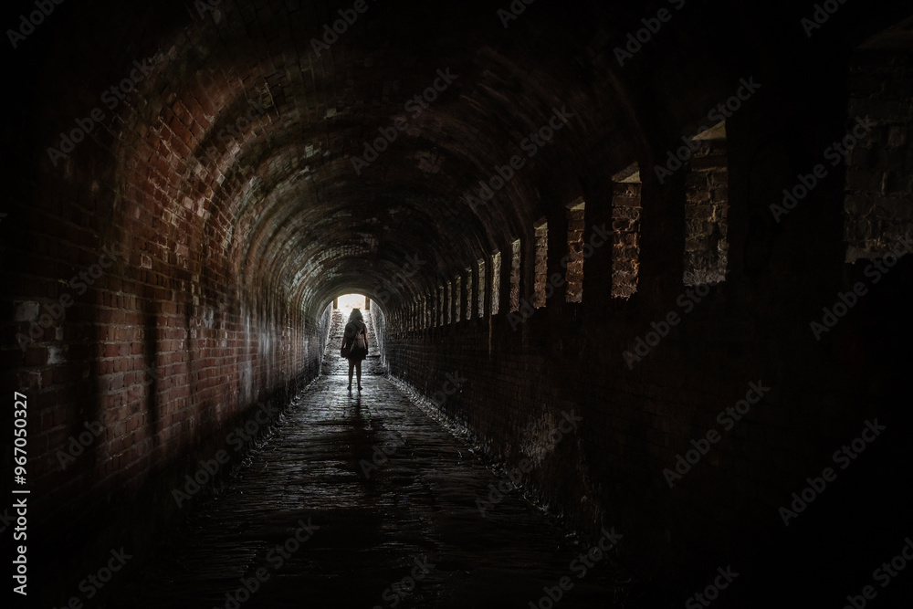 Naklejka premium lady female tourist walks through Stenen Beer stone bear part of fortification with walkable tunnel passageway Veere, Zeeland, Netherlands