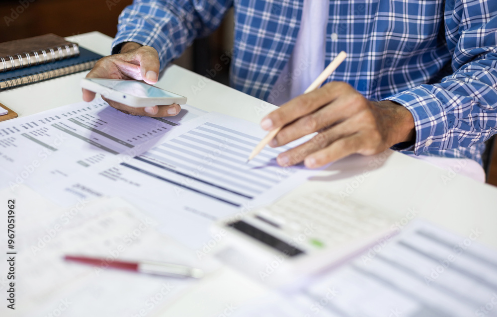 Asian man using smart phone doing online business calculate income and expenses from business document, checking financial report after start new business owner Asian man using smart phone doing online business calculate income and expenses from business document, checking financial report after start new business owner