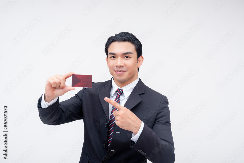 A confident young asian business executive smiling while pointing to a blank card. Possible reward, membership or debit card. Isolated on a white background. A confident young asian business executive smiling while pointing to a blank card. Possible reward, membership or debit card. Isolated on a white background.