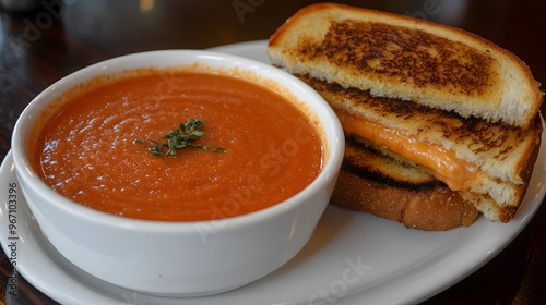 23. A bowl of rich and creamy tomato soup with a grilled cheese sandwich on the side photo