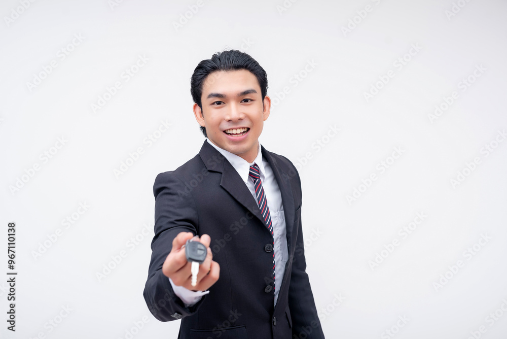 A happy young asian car salesman handing over the keys to a new car. Isolated on a white background. A happy young asian car salesman handing over the keys to a new car. Isolated on a white background.