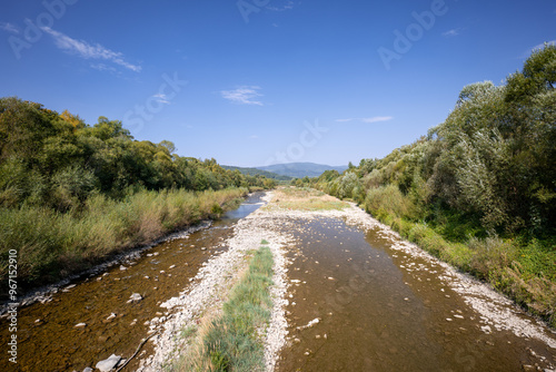 Obraz na płótnie Beautiful mountain landscape on a sunny day. Natural coastline. A small amount of water in the river. Beskid Mountains. The Soła River. View from the