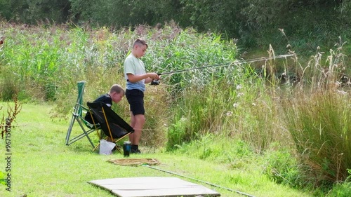 Young boys, boy fishing along the riverbank, Summer days angling by the river lake. Sitting peacefully and enjoying the lazy day photo