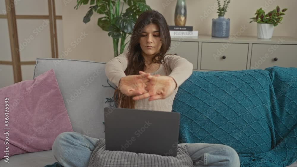 Attractive young woman stretching while using a laptop in the cozy interior of a living room with colorful decor and potted plants. Attractive young woman stretching while using a laptop in the cozy interior of a living room with colorful decor and potted plants.