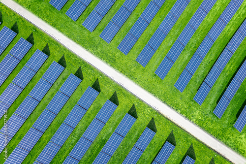 Overhead view from a drone over of a large array of solar panels on a solar farm with rows of modern photovoltaic solar panels in a green agricultural field. Agrivoltaics concept in Spain