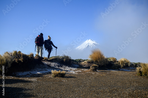 Obraz na płótnie Couple looking at Snow-capped Mt Taranaki in the clouds. Pouakai Circuit track. New Zealand. w salonie