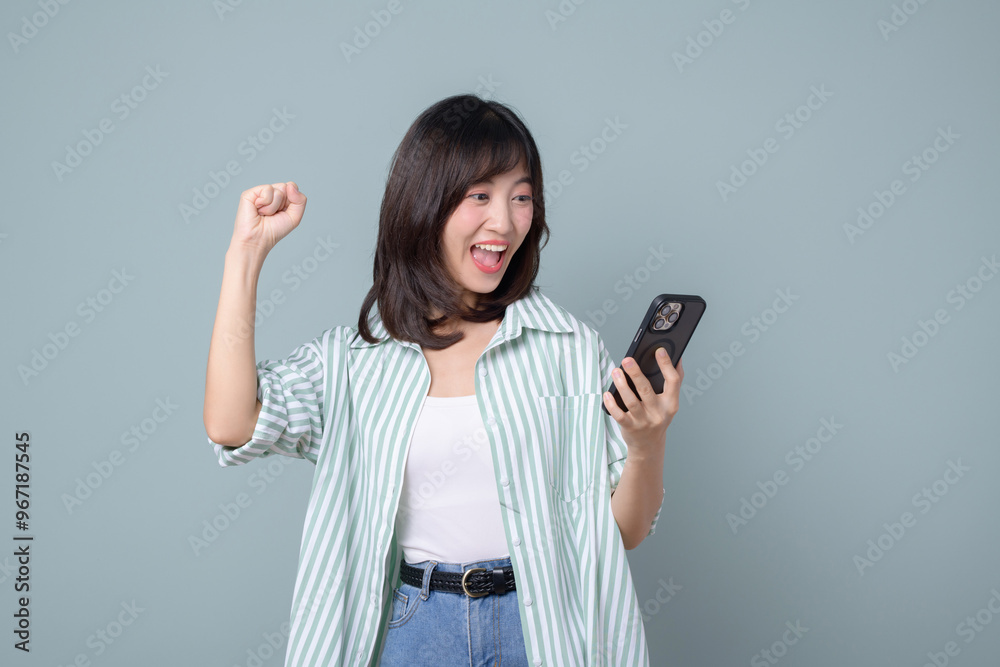 Happy asian woman do winner dance, triumphing, winning on mobile phone video game, holding smartphone horizontal position and celebrating, green background Happy asian woman do winner dance, triumphing, winning on mobile phone video game, holding smartphone horizontal position and celebrating, green background