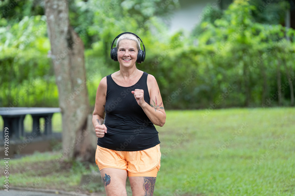 Elderly woman smiling while jogging in park Elderly woman smiling while jogging in park