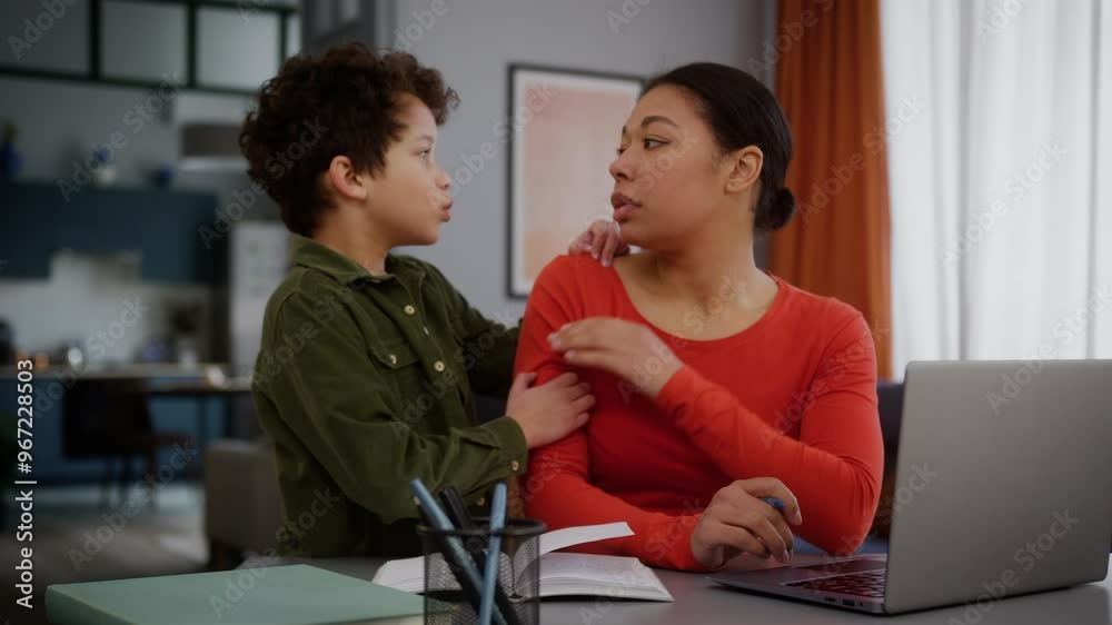 African American family upset tired multitasking mother woman female freelancer girl business task write working home laptop little child kid son sad boy come in ask need attention mom say no ignore
