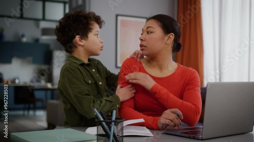 African American family upset tired multitasking mother woman female freelancer girl business task write working home laptop little child kid son sad boy come in ask need attention mom say no ignore photo