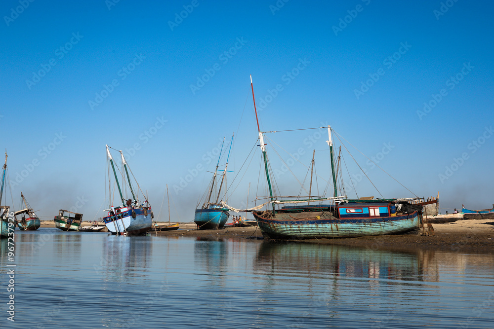 Traditional fishing boats lined along the riverbank in Morondava, Madagascar during a sunny day Traditional fishing boats lined along the riverbank in Morondava, Madagascar during a sunny day