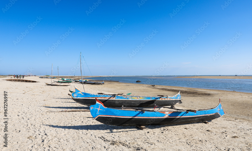 Fototapeta premium Beach activity along the coastline of Madagascar featuring traditional fishing boats under a clear blue sky
