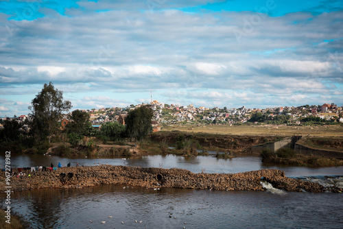 Panoramic view of a river and settlements in a suburb of Antananarivo, Madagascar, under a vibrant sky during the day