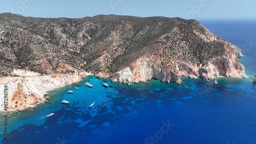 Aerial drone photo of paradise blue bay of uninhabited island of Polyaigos with turquoise crystal clear sea visited by luxury yachts and sail boats resembling a blue lagoon, Cyclades, Greece photo