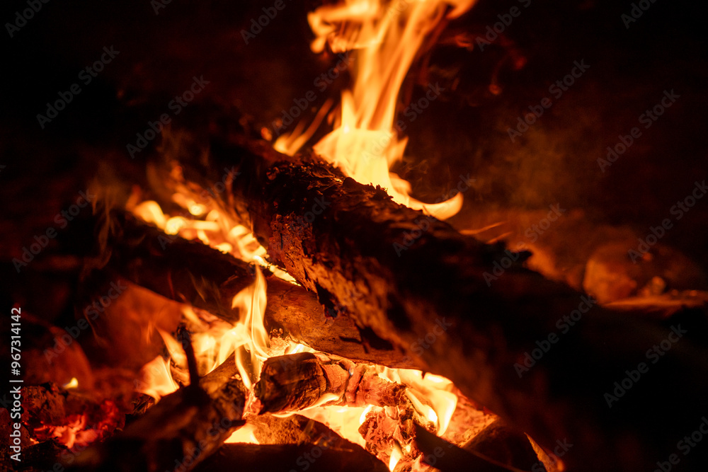 Flames flicker and crackle as they consume wooden logs, providing warmth and ambiance on a chilly night Flames flicker and crackle as they consume wooden logs, providing warmth and ambiance on a chilly night