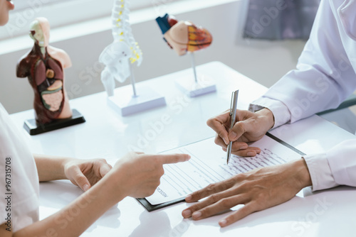 Asian male doctor consults with patient in clinic, reviews medical documents and uses stethoscope to diagnose health conditions, and confidently provides professional advice and care.