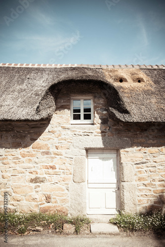 Detail of a traditional thatched roof cottage house in the charming Village of Kercarnic, Brittany (Bretagne), France. Vertical shot. photo