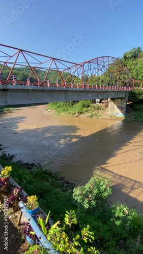 4k vertical video footage of suspension bridge built over the Oya river, Imogiri, Yogyakarta, Indonesia with murky river water stream and clear blue sky in the morning. photo