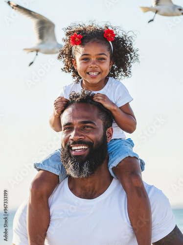 Portrait of a happy African American father carrying his daughter on his shoulders at the beach
