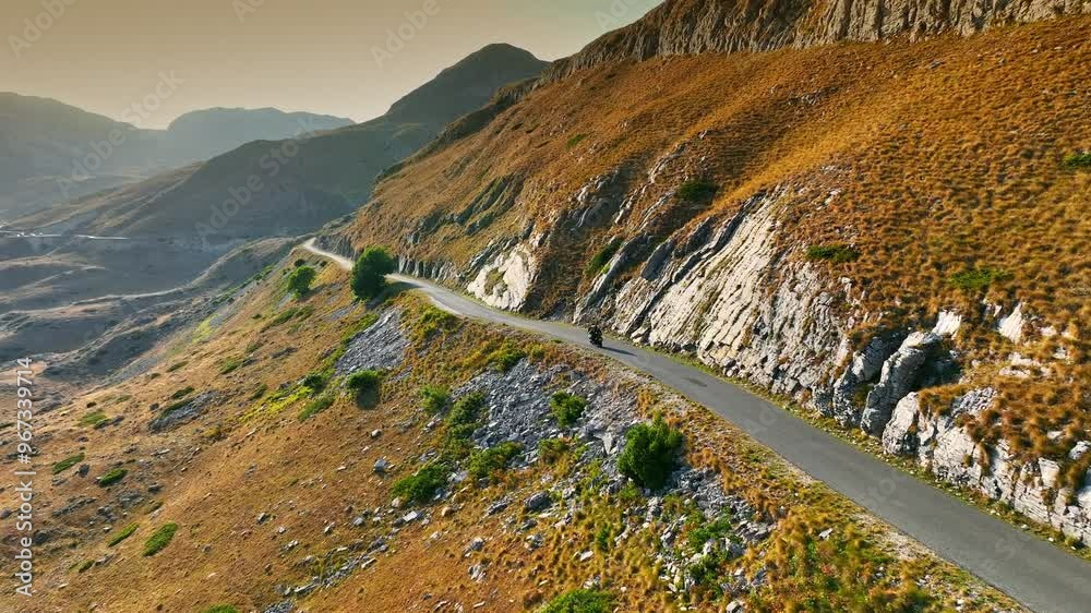 Fast sports motorcycle rides on mountain road with serpentines. Traveling together on motorbike concept. Summer adventure in the mountains. Aerial drone shot