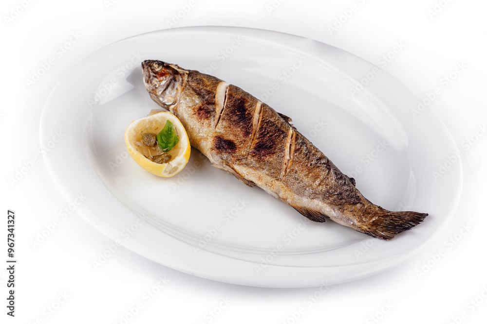 Grilled trout lying on white plate with lemon and capers Grilled trout lying on white plate with lemon and capers