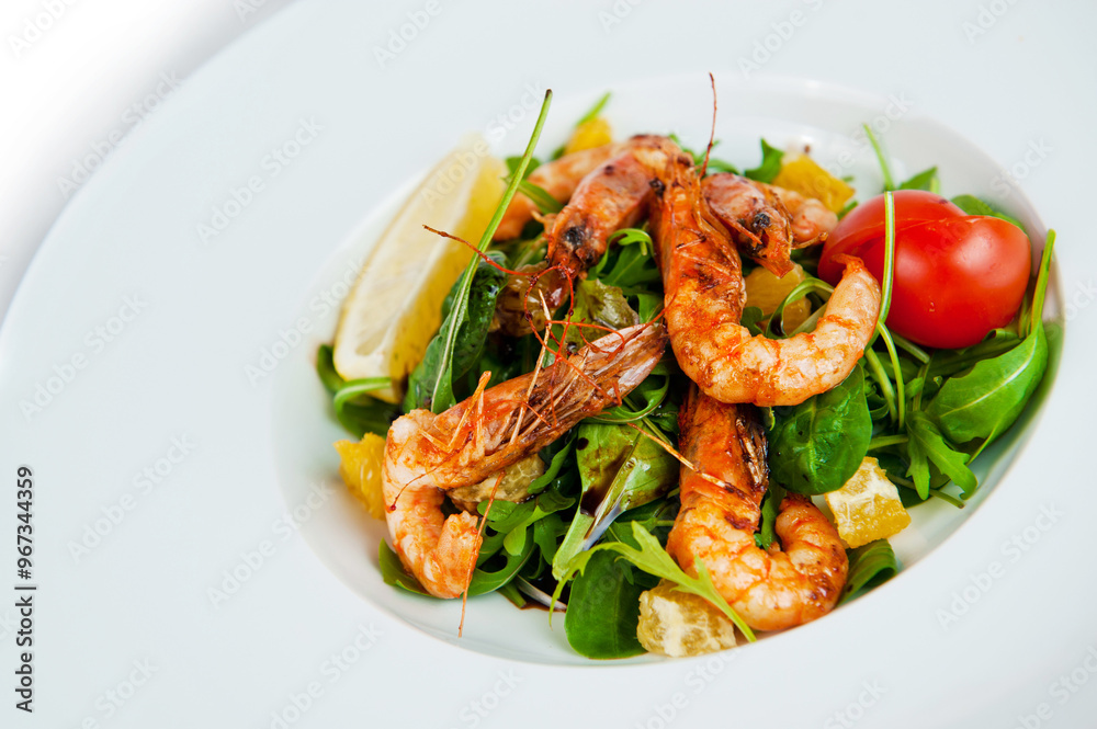 Delicious salad with grilled shrimps, arugula and orange slices on white plate
