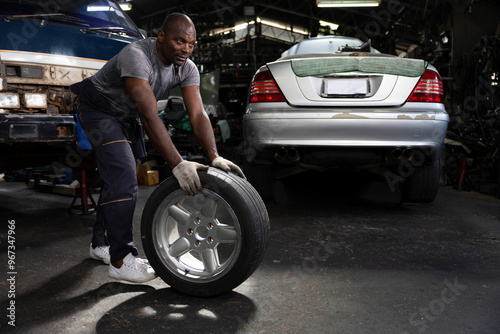 mechanic holding and pushing a tire for fixing in garage