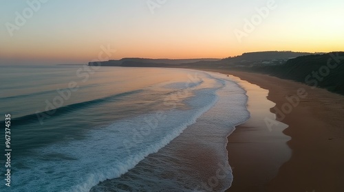 Serene beach at sunset with gentle waves and cliffs.