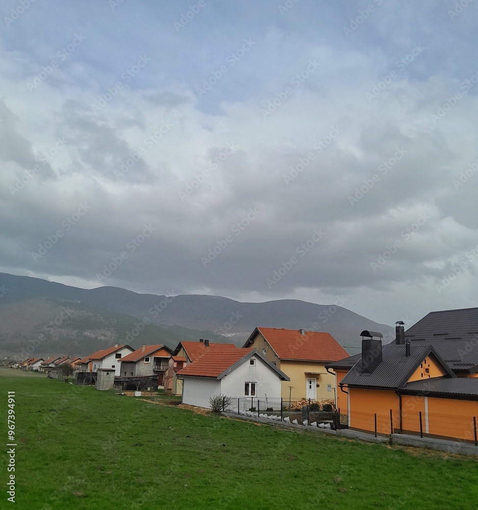 Panorama of country life: houses with red roofs against the backdrop of a mountain landscape Panorama of country life: houses with red roofs against the backdrop of a mountain landscape