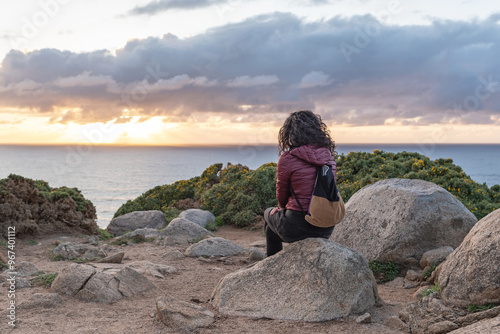 Woman contemplating the sunset in Estaca de Bares. Coruña, Galicia.