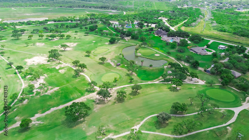 Sand trap and pond in country golf course near Hazel Park, Corpus Christi, South Texas, surrounding residential neighborhood upscale houses with swimming pool, grassy backyard, tall trees, aerial