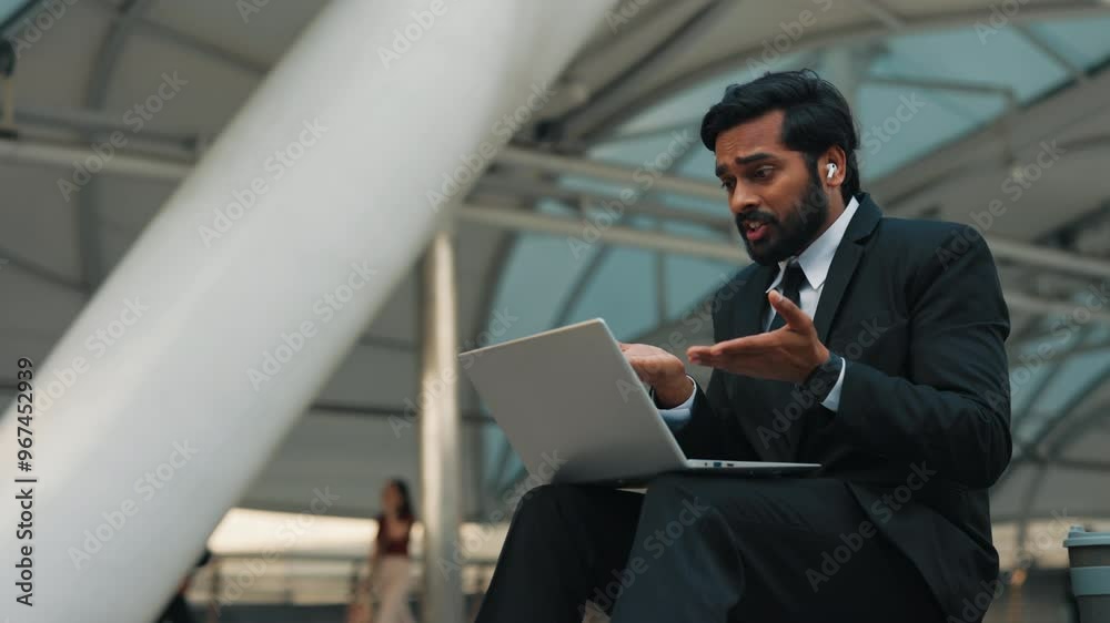 Worried startup runner in formalwear sitting in modern working hub and talking during video call. Brunette male having discussion with distant employees and controlling accuracy of assigned task.