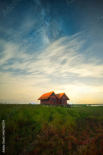 The milky way and Cloudy over old twin houses at Thale noi lake, Phatthalung, Thailand. photo