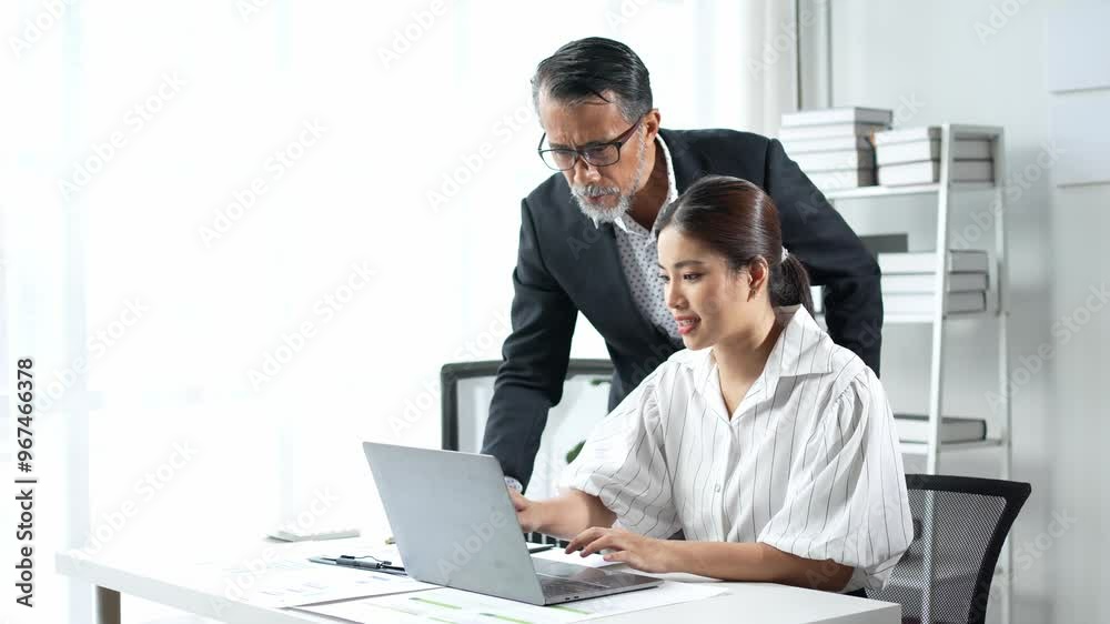 Senior manager helping young employee using laptop at office Senior manager helping young employee using laptop at office