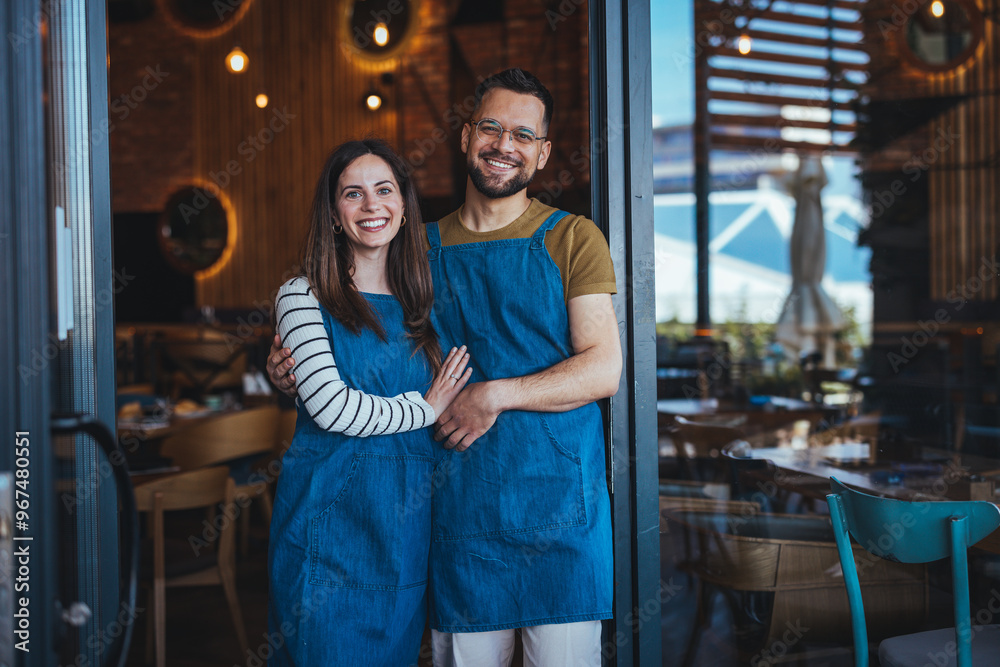 Smiling Couple Standing in Front of Their Cozy Restaurant Smiling Couple Standing in Front of Their Cozy Restaurant