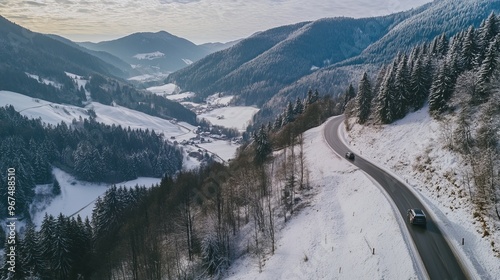 Car drives on a snowy mountain road, surrounded by green mountains. It's a winter wonderland in Europe, Bavaria, Germany.