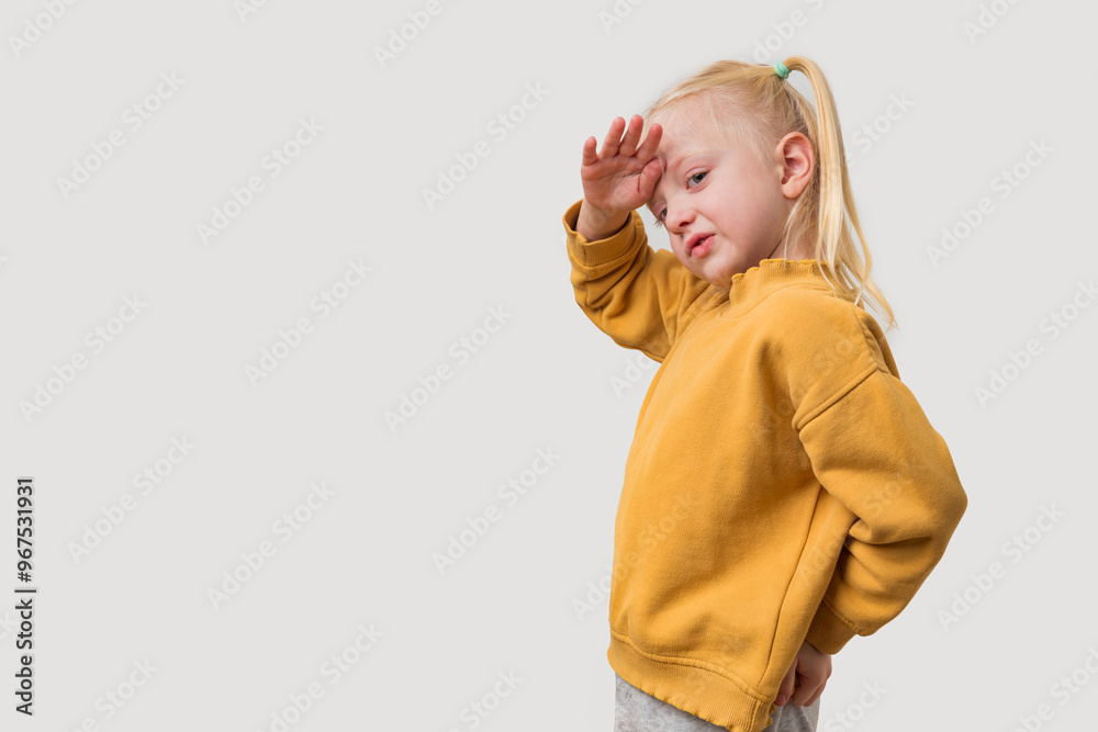 Portrait of a little girl with blond hair in a yellow hoodie on a white background. Portrait of a little girl with blond hair in a yellow hoodie on a white background.