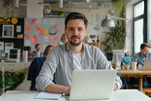 Happy professional business man company employee, young entrepreneur, smiling businessman working on laptop computer technology looking at camera working in office sitting at desk, portrait.