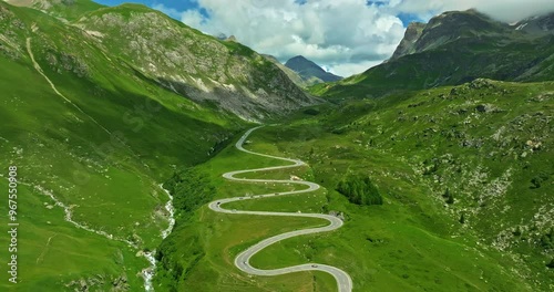 Aerial flyover over the turns of Maloja pass in Swiss. Aerial view of cars on road trip across the mountains of Switzerland drive along hairpin turns. Aerial drone view winding mountain road