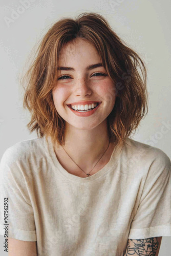 Joyful European Woman, A cheerful European woman with a bob hairstyle laughs brightly, showing her white teeth She wears a casual t-shirt and has a tattoo