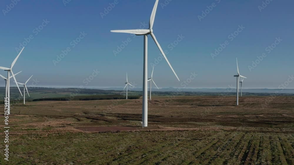 Aerial view of a beautiful wind farm with numerous wind turbines in a green landscape, East Kilbride, United Kingdom. Aerial view of a beautiful wind farm with numerous wind turbines in a green landscape, East Kilbride, United Kingdom.